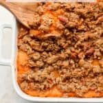 A square dish of sweet potato casserole with pecans.