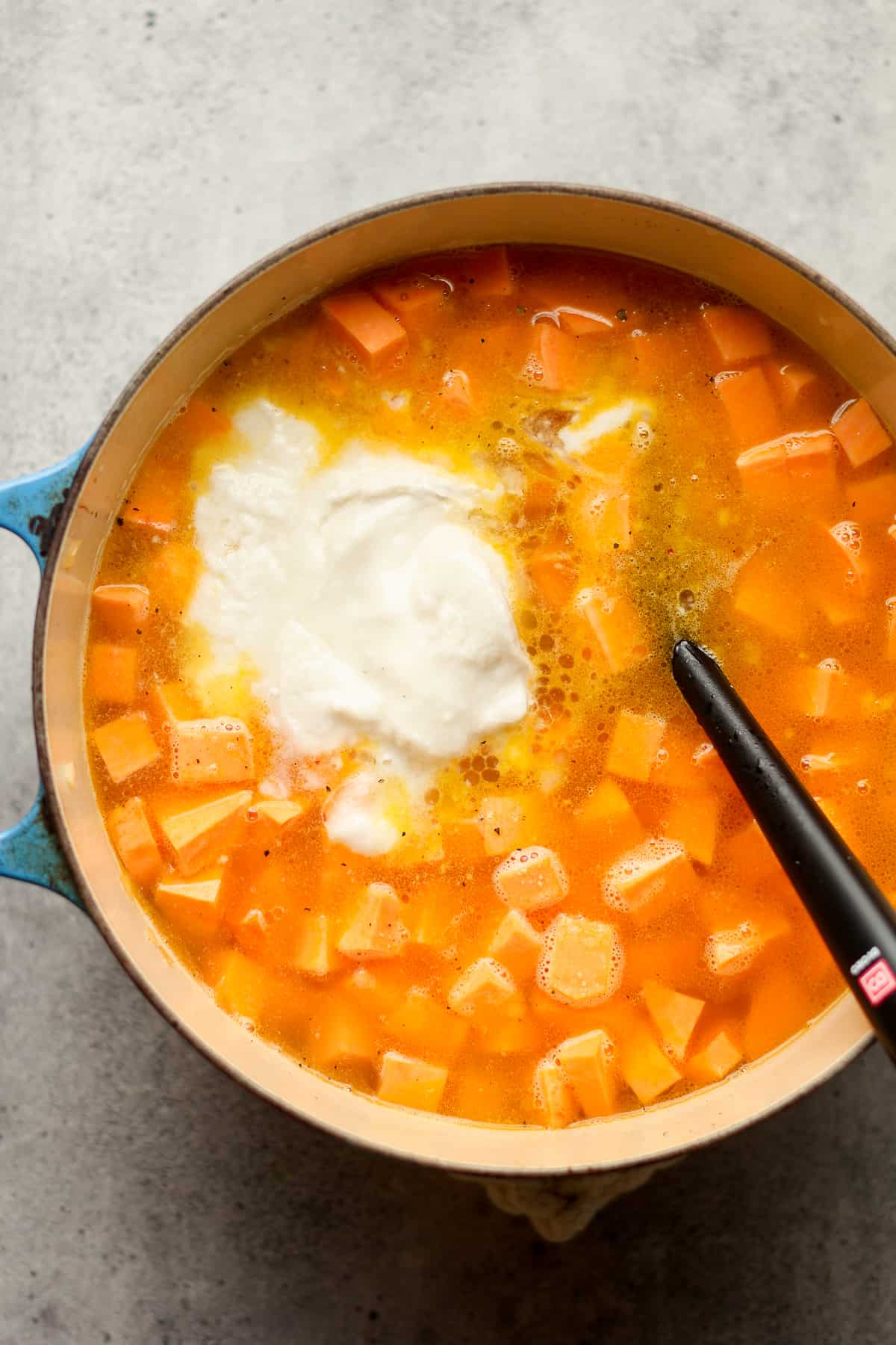 The pot of soup with chunks of sweet potatoes and the coconut on top.