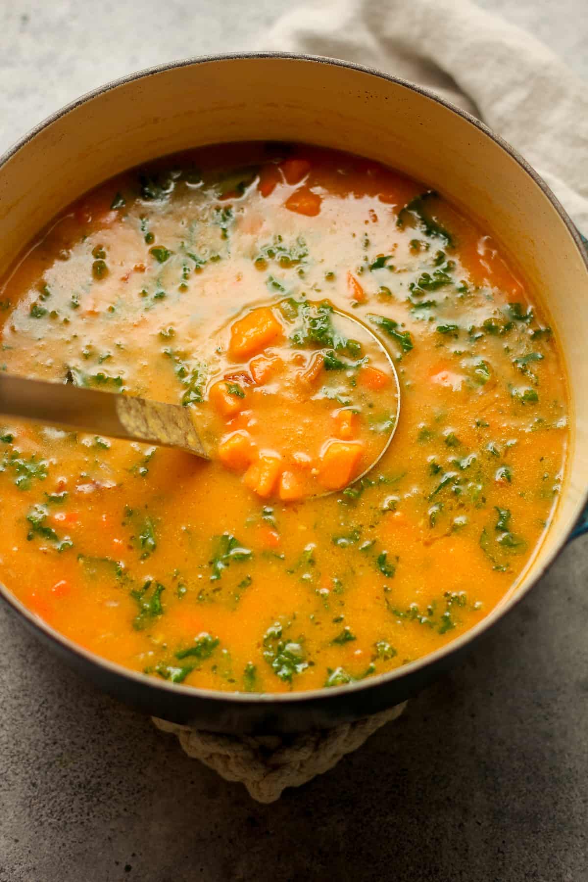 A pot of sweet potato soup with a soup ladle.