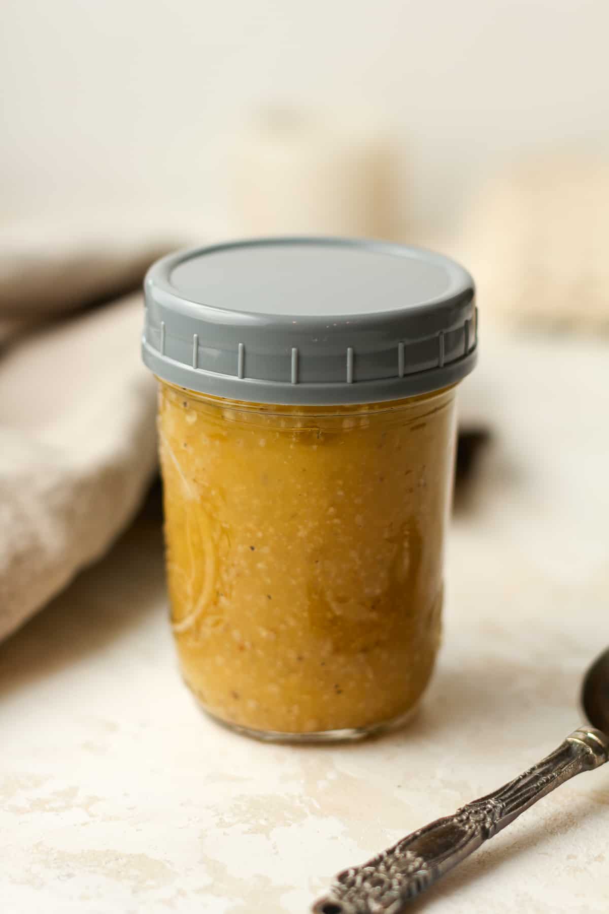 Side view of a jar of dressing with a lid.