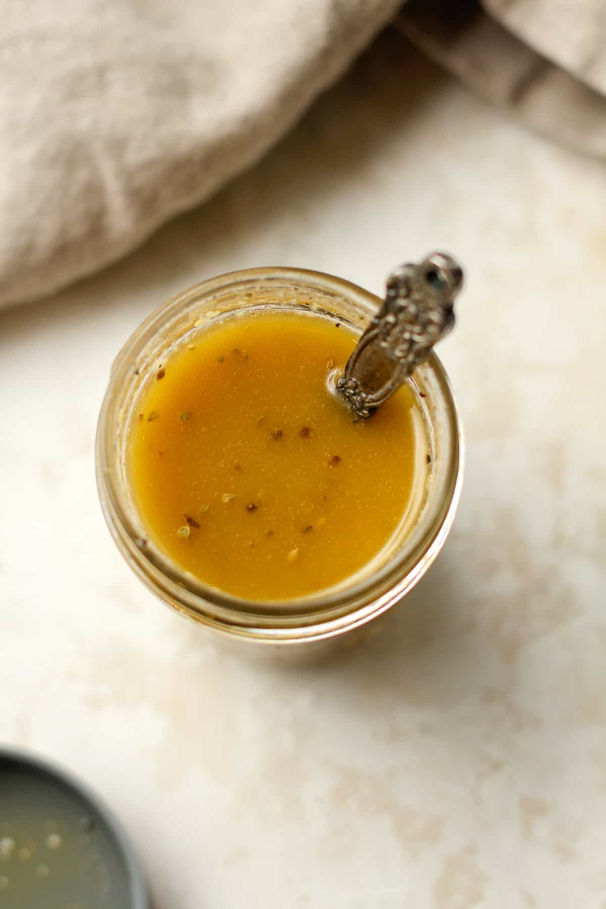 Overhead view of a jar of Italian dressing with a spoon.