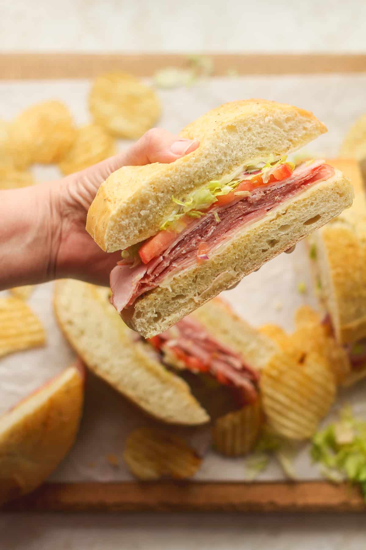 A hand holding a wedge of the Italian grinder sandwich.