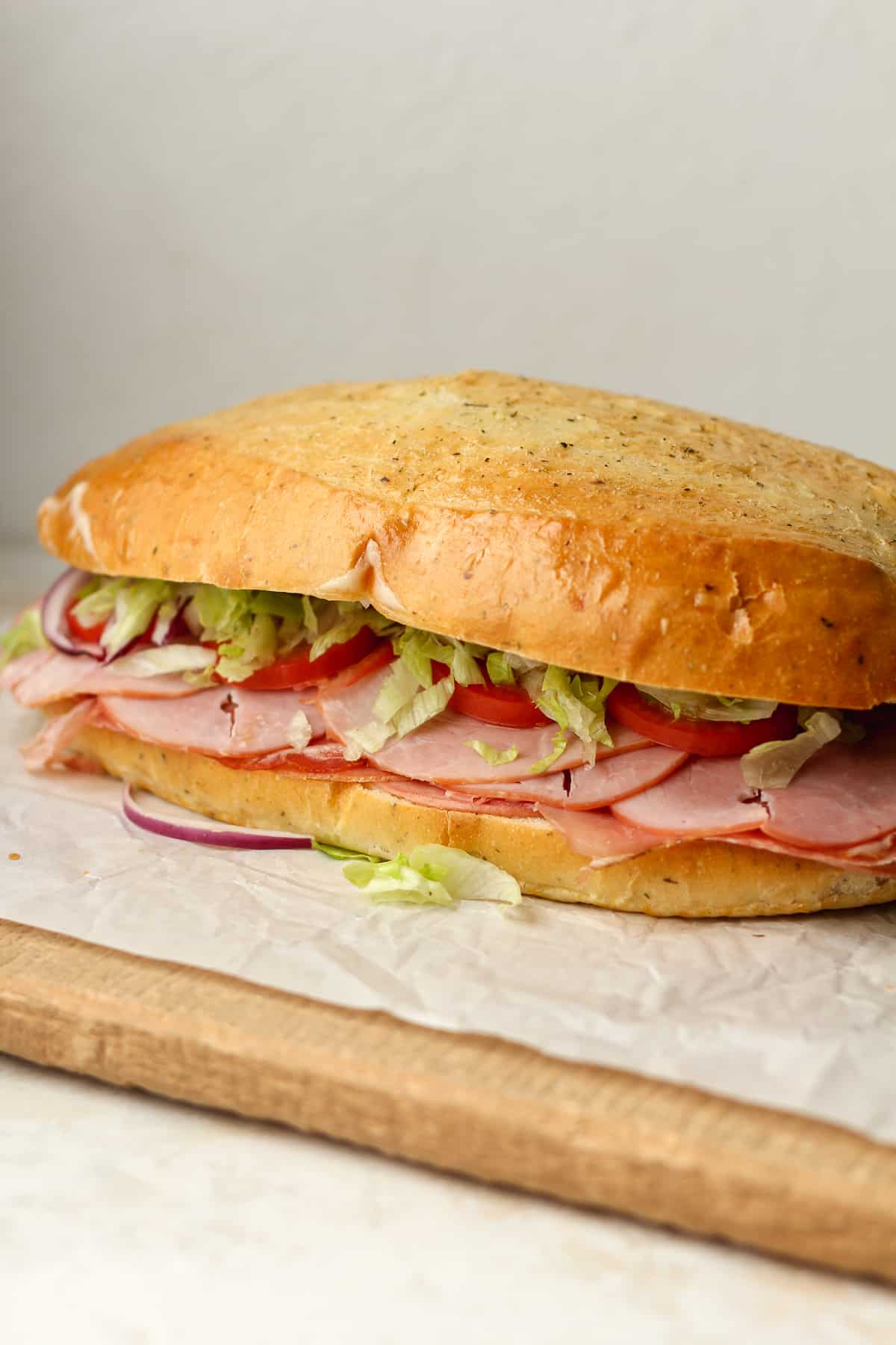 Side view of a large Italian sub sandwich, with layers of Italian meats and cheese, with lettuce and tomato.