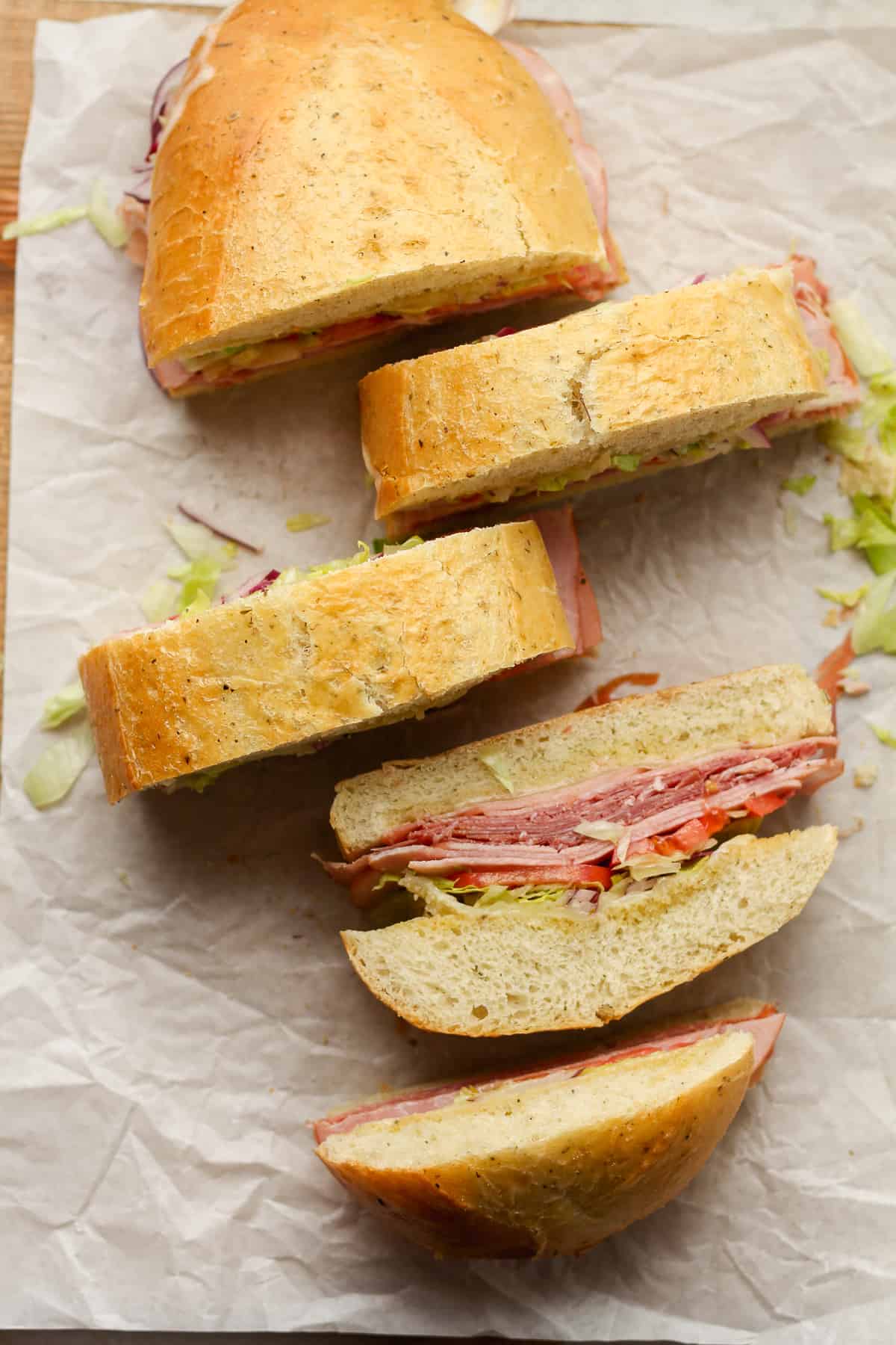 Overhead view of a large loaf of Italian subs, some sliced.