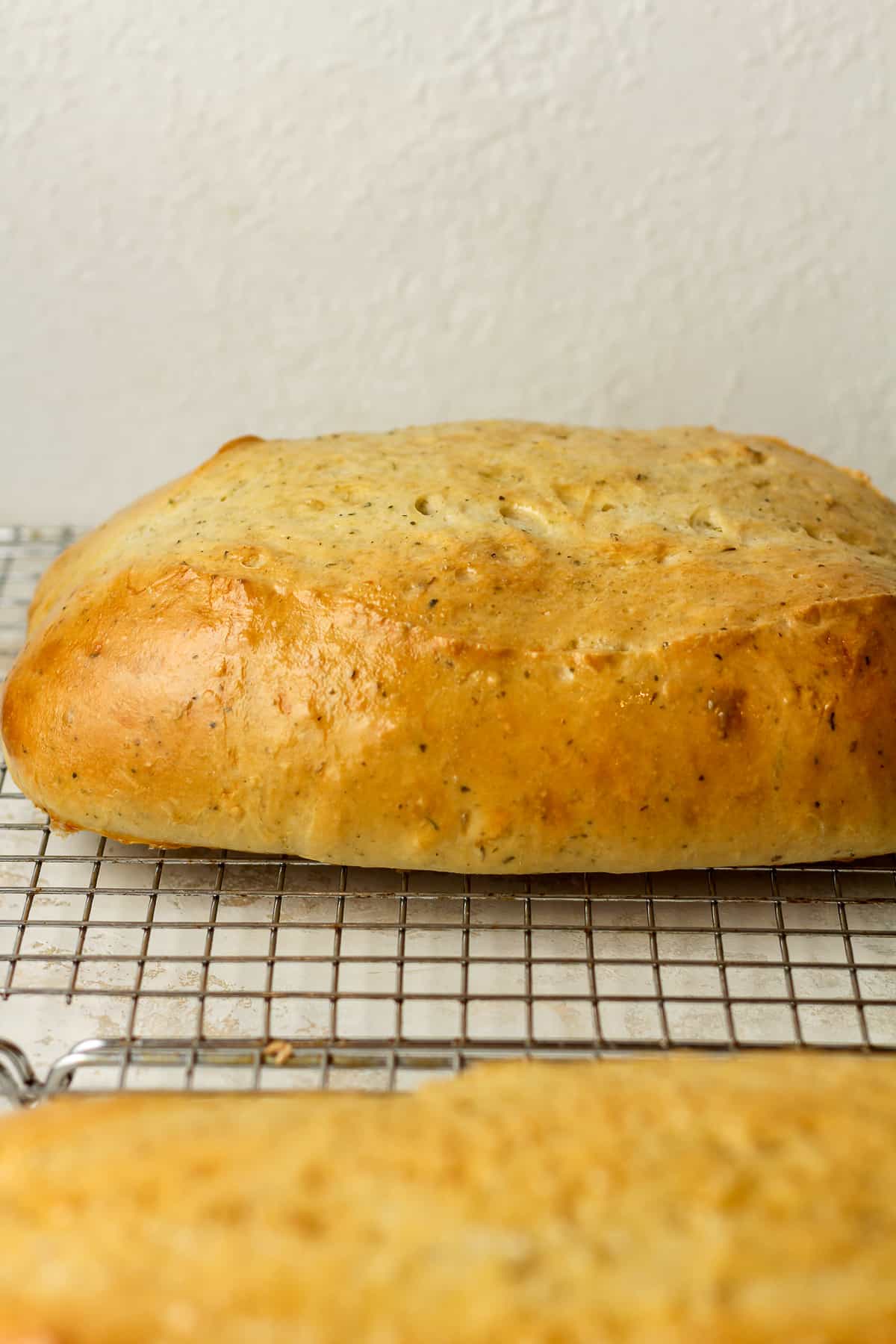 Side view of two loaves of bread with Italian herbs.