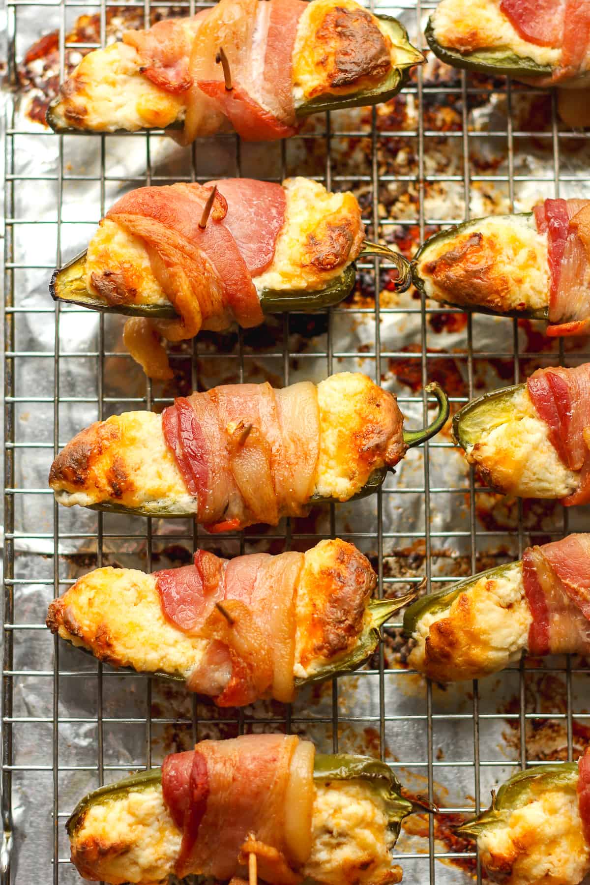 Some just roasted jalapeno poppers on a wire rack on a sheet pan.