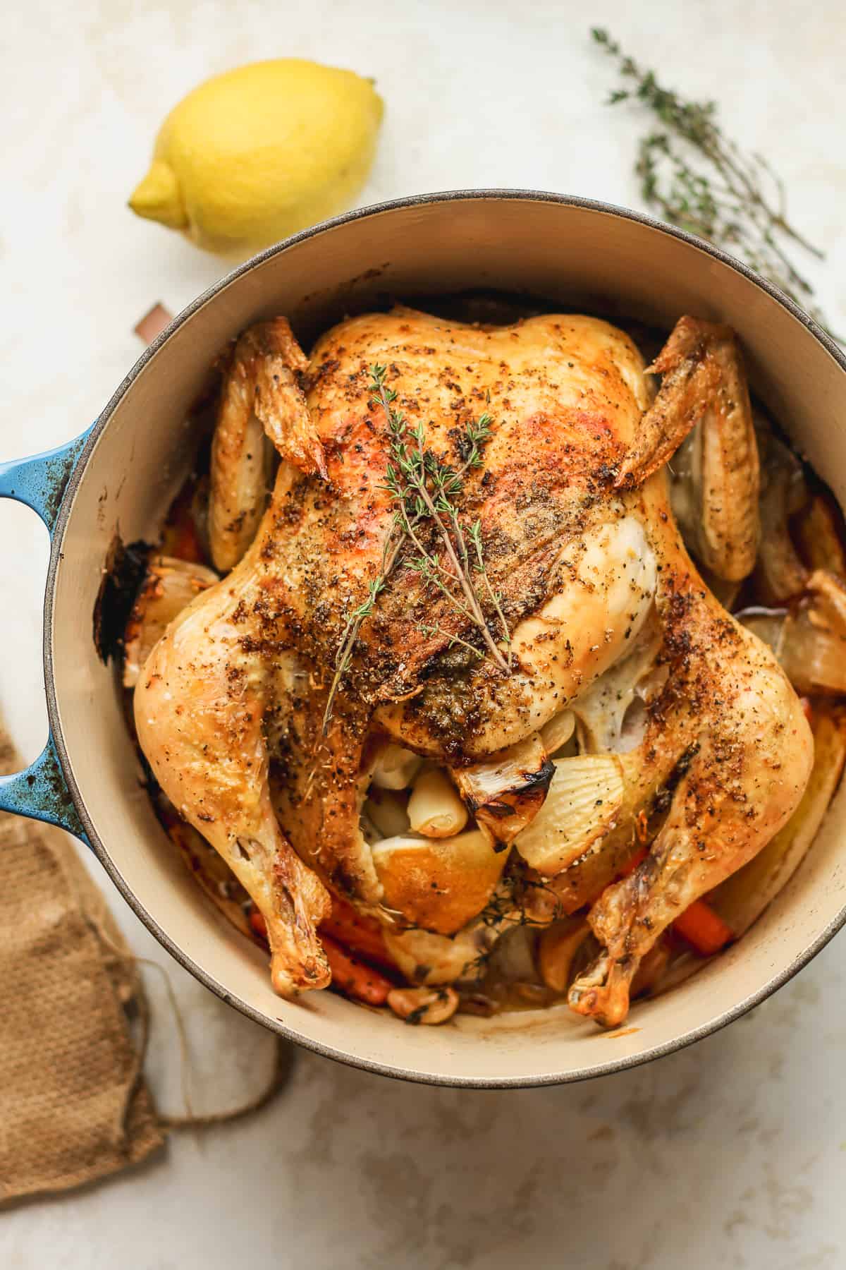 A dutch oven with a crispy whole roasted chicken with thyme.