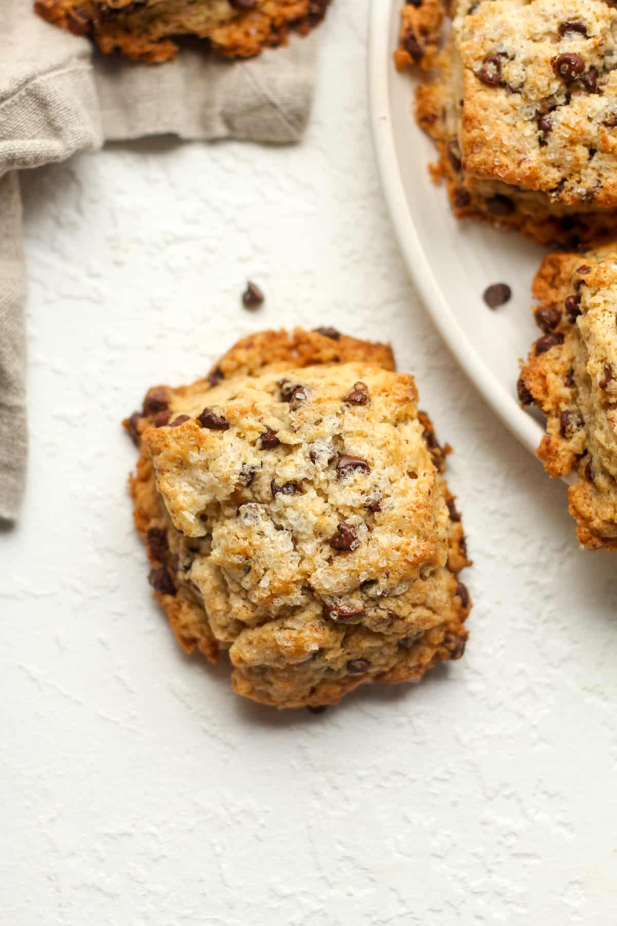 A chocolate chip scone next to a plate of scones.