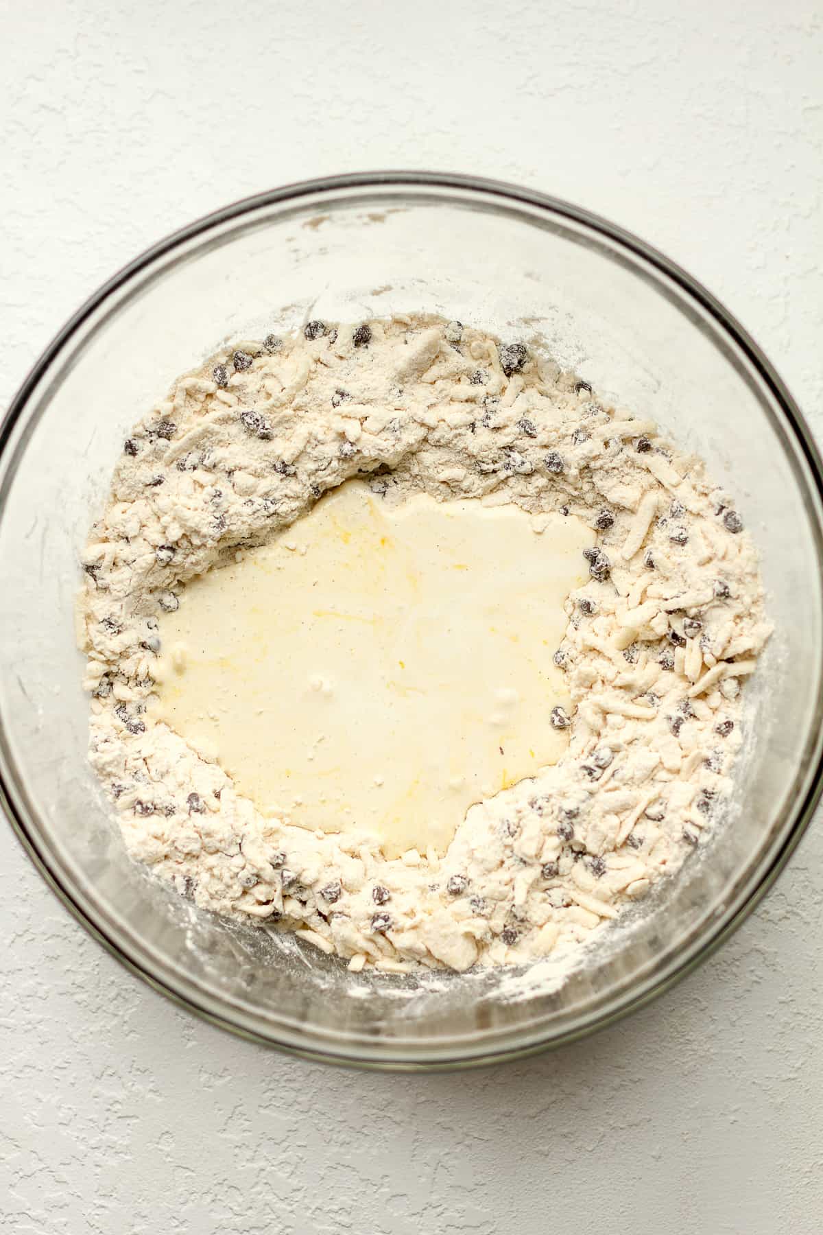 A bowl of the dry ingredients with the cream and egg on top.