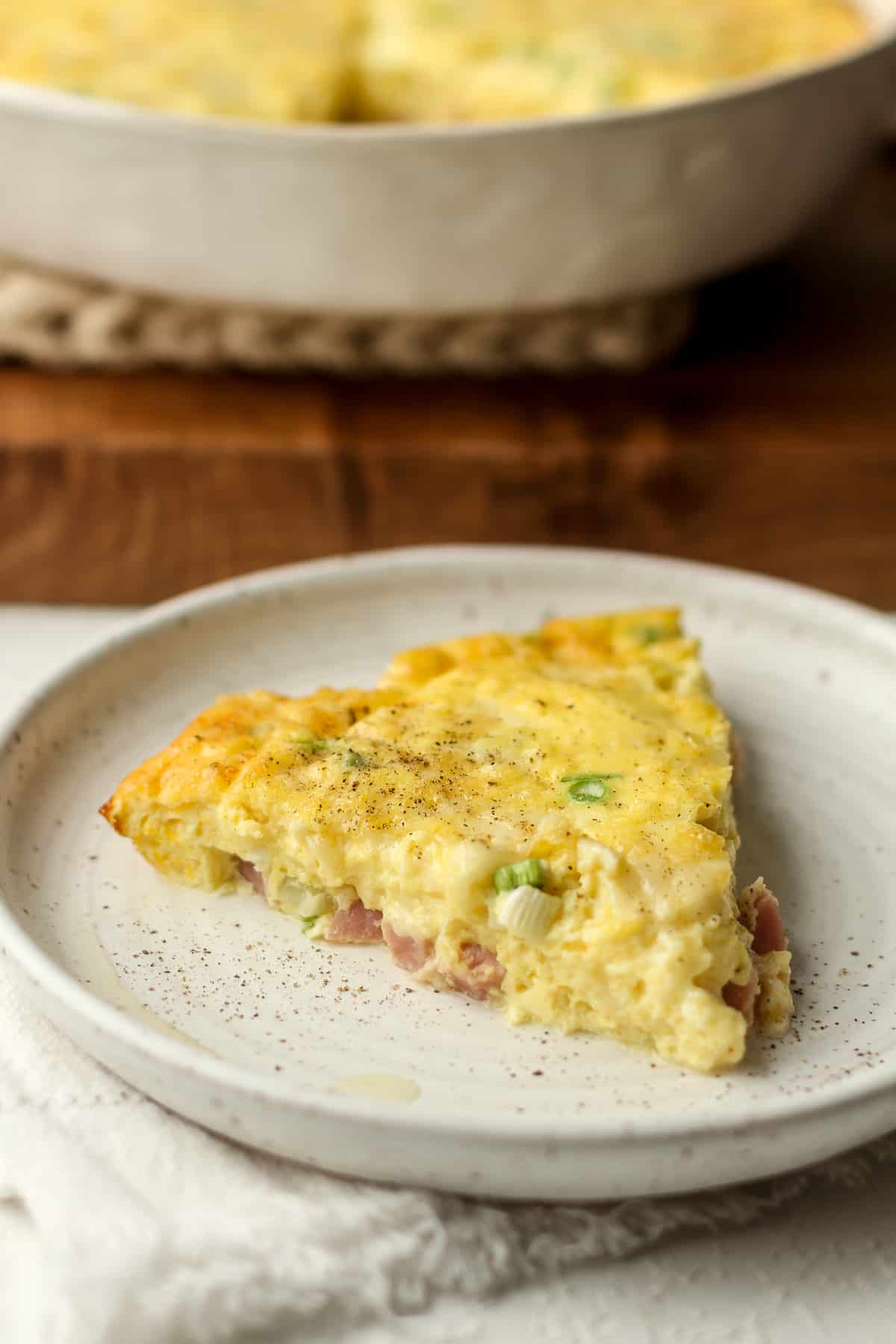 Side view of a slice of quiche with ham.