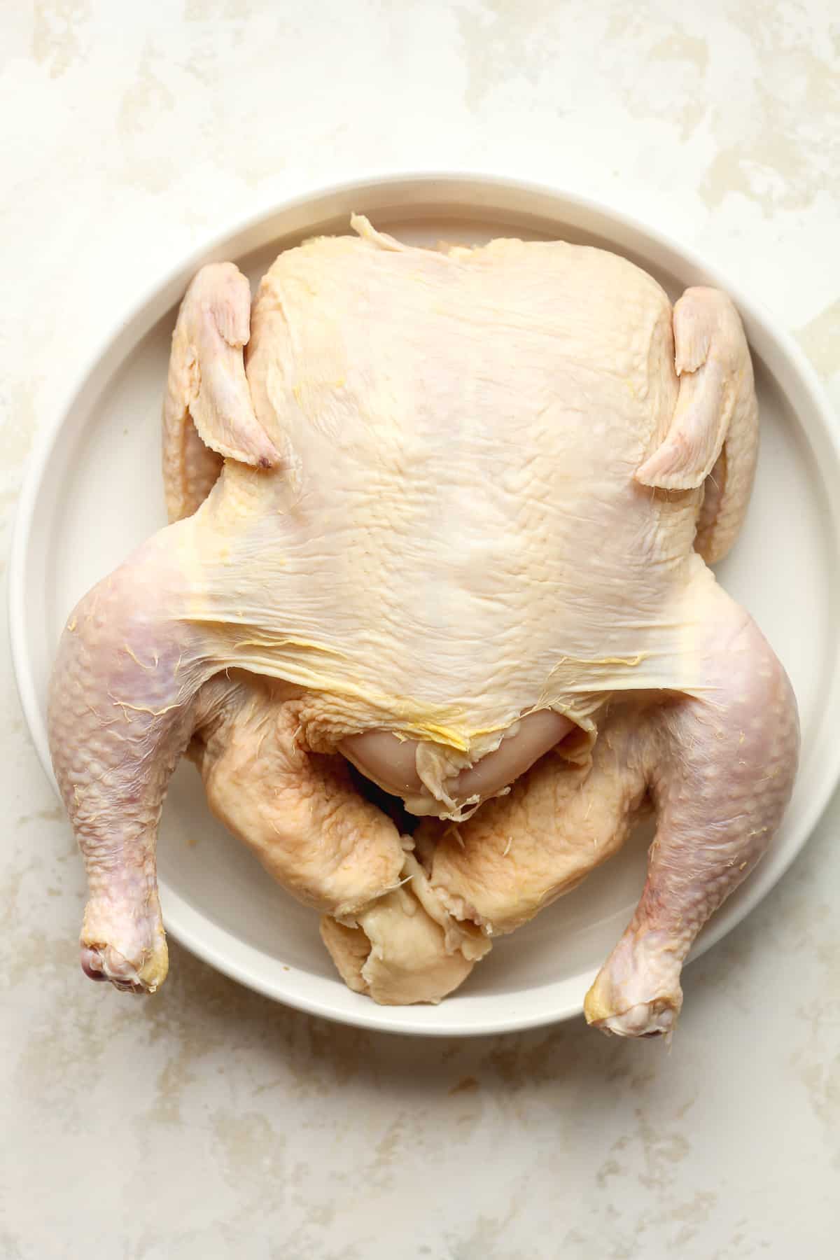 A raw chicken in a white tray.