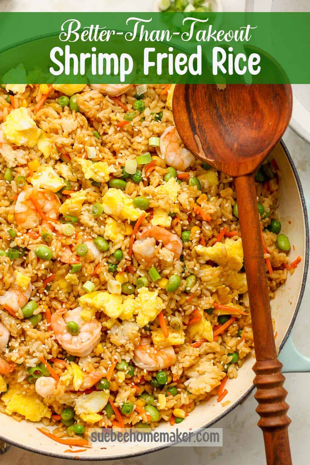 A large pan of shrimp fried rice with a wooden spoon.