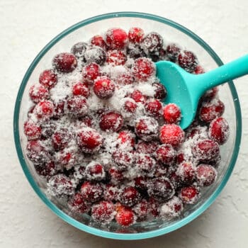 A bowl of sugared cranberries with a blue spatula.