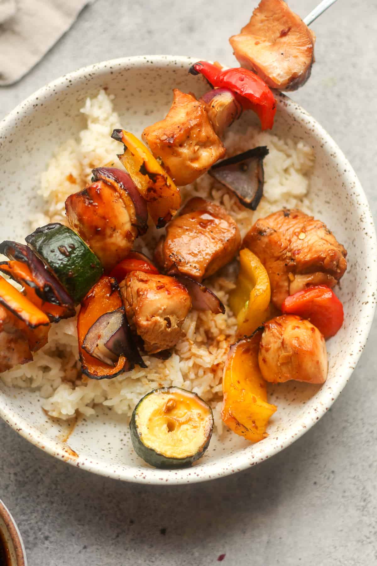 A close upon a bowl of Asian skewers over rice.