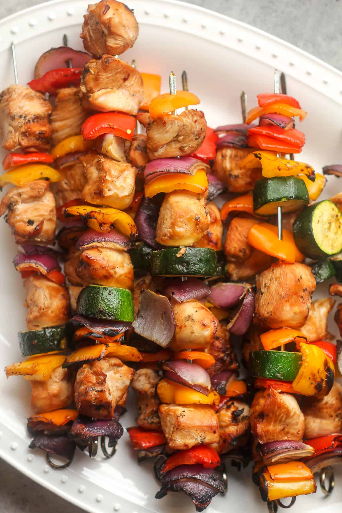 A closeup on some Asian chicken skewers on a white tray.