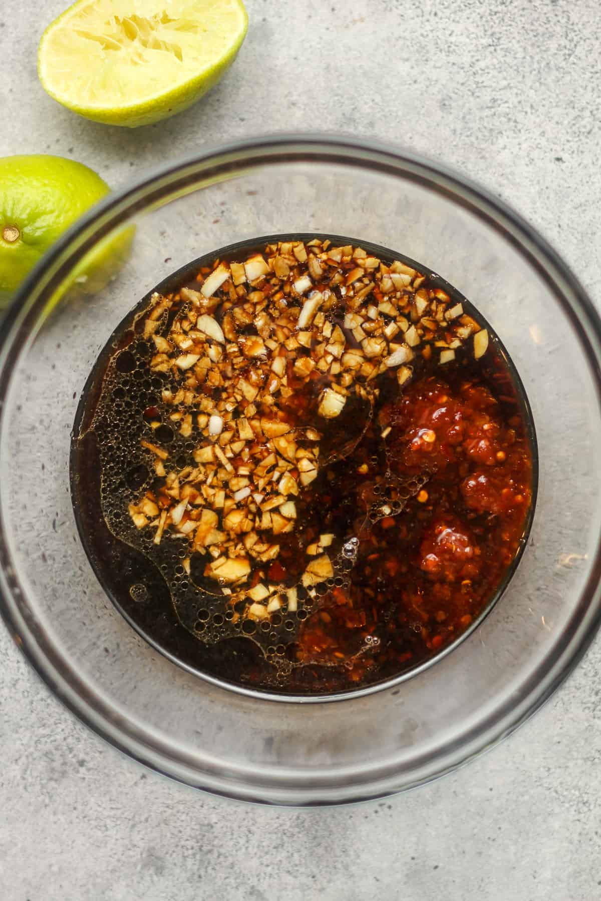 The Asian marinade in a bowl with limes.