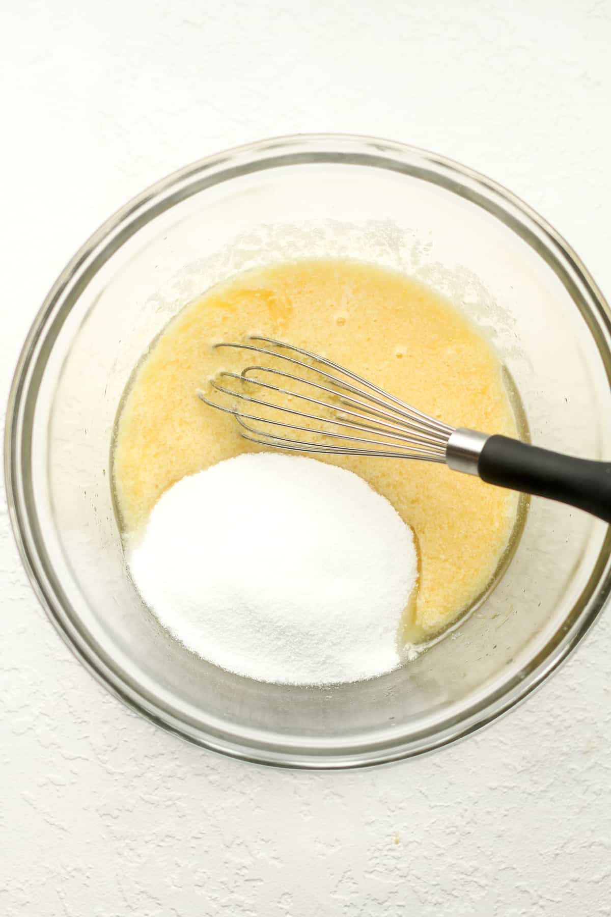 A bowl of the wet ingredients with sugar on top.