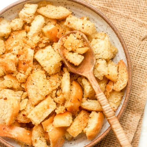 Overhead view of a bowl of homemade croutons with a spoon.