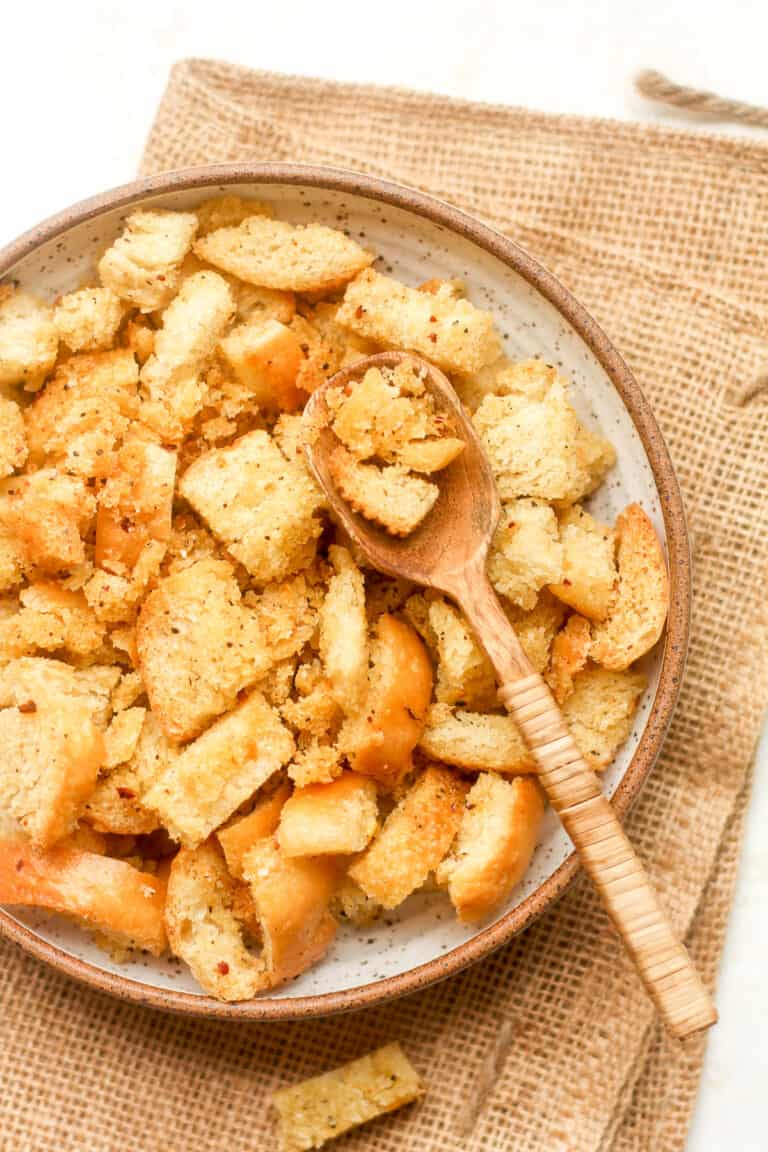 Overhead view of a bowl of homemade croutons with a spoon.