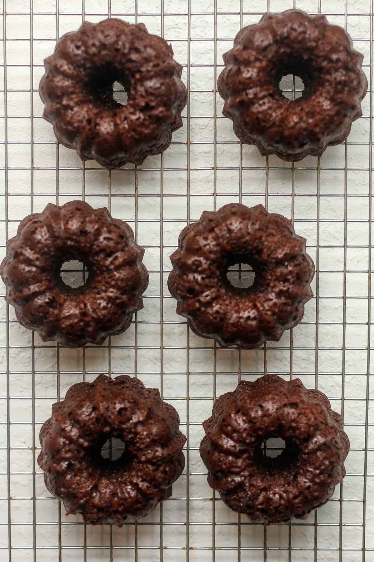 A wire rack of just baked chocolate bundt cakes - mini style.