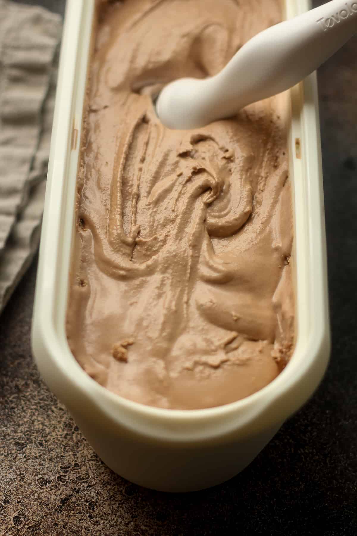 A large tub of nutella ice cream with an ice cream scoop.