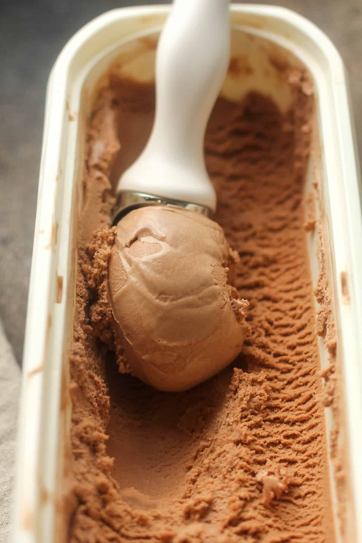 A large tub of nutella ice cream with a scoop being rolled up.