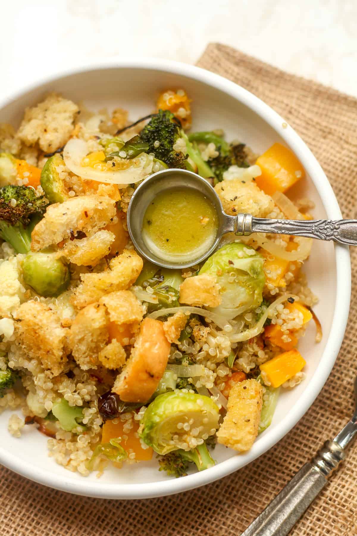 Closeup on a serving of roasted vegetable quinoa salad with a tablespoon of lemon dressing.