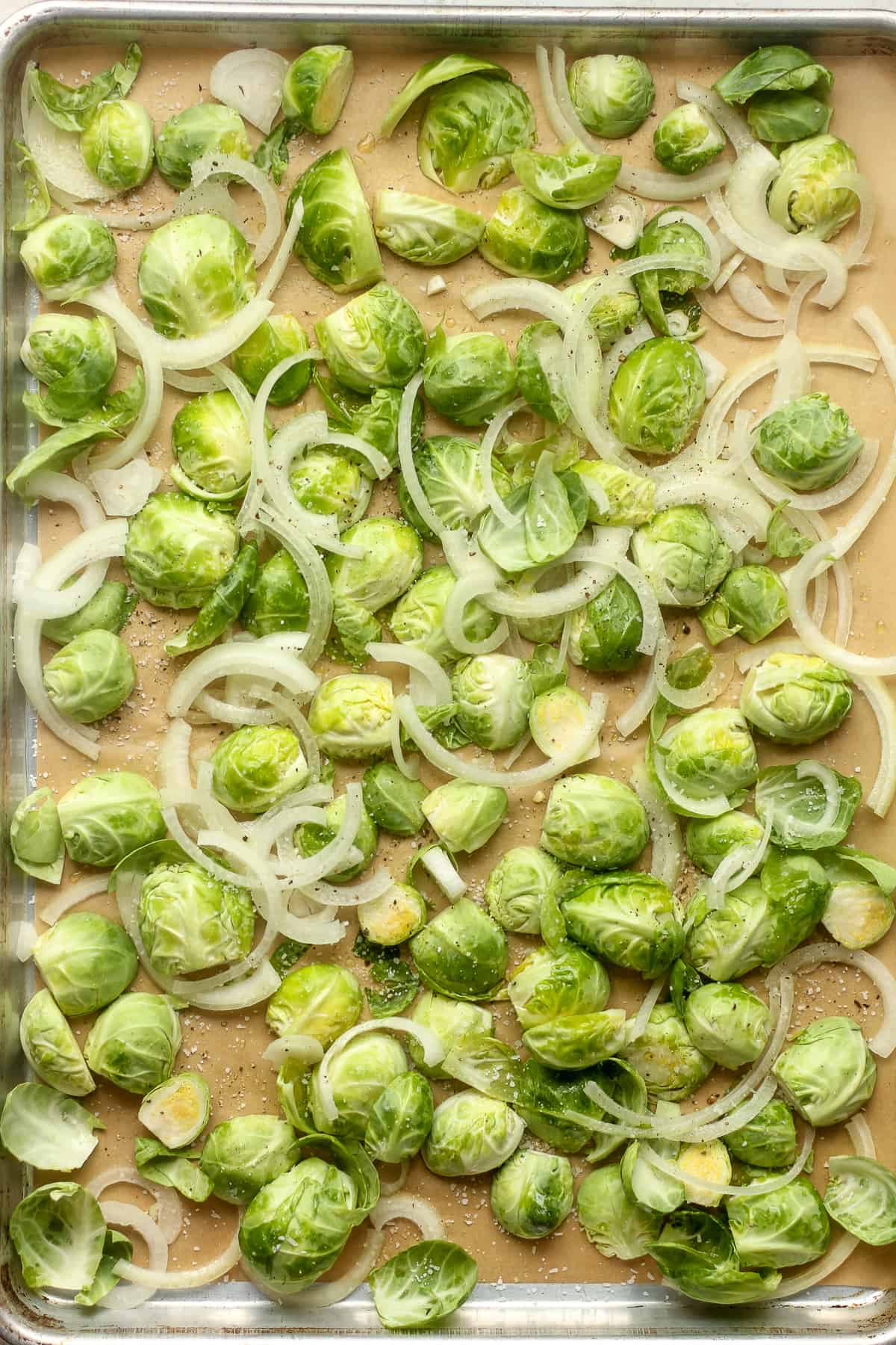A pan of the raw brussels sprouts and sliced onion.