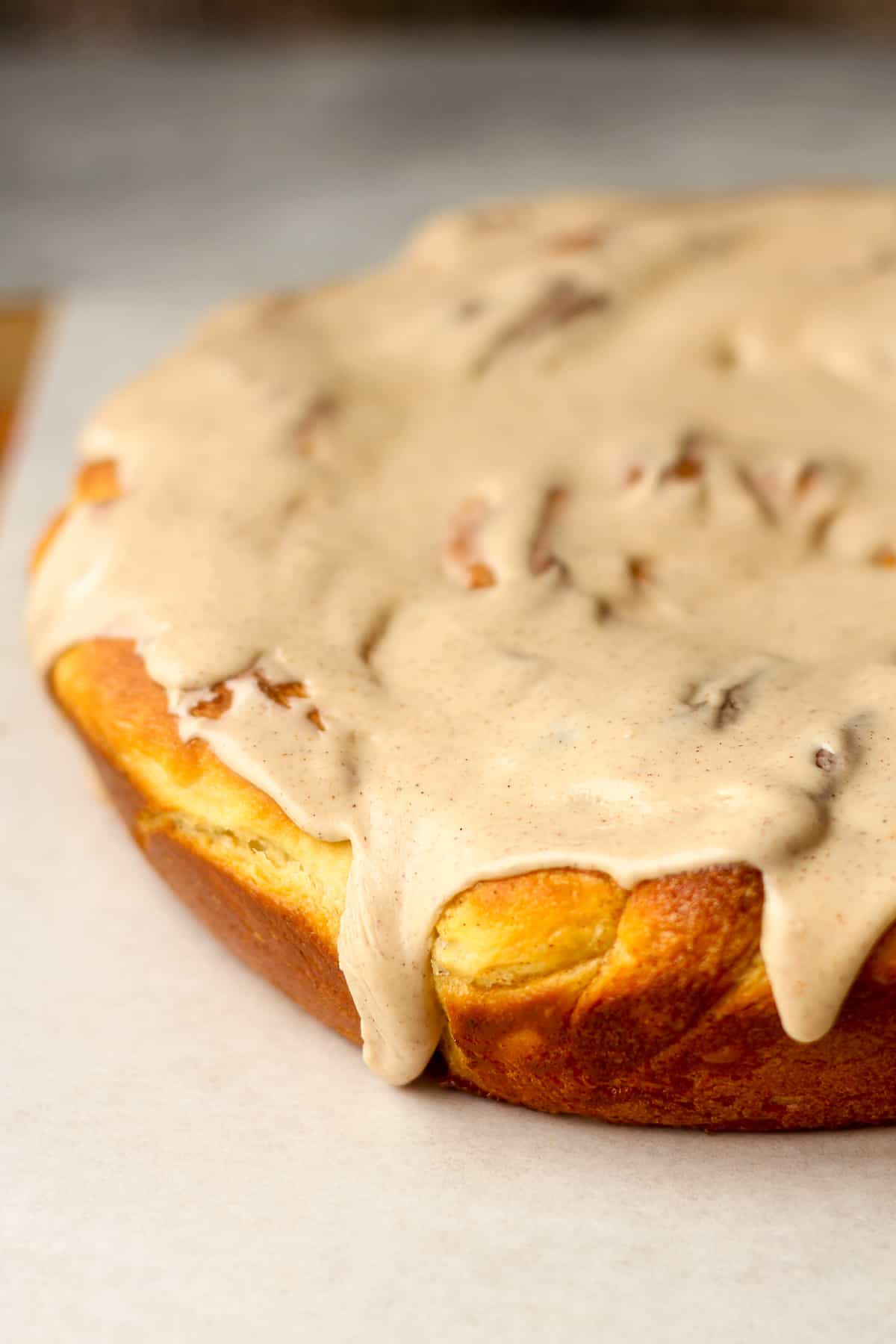 Side view of a large cinnamon twist roll with maple icing.
