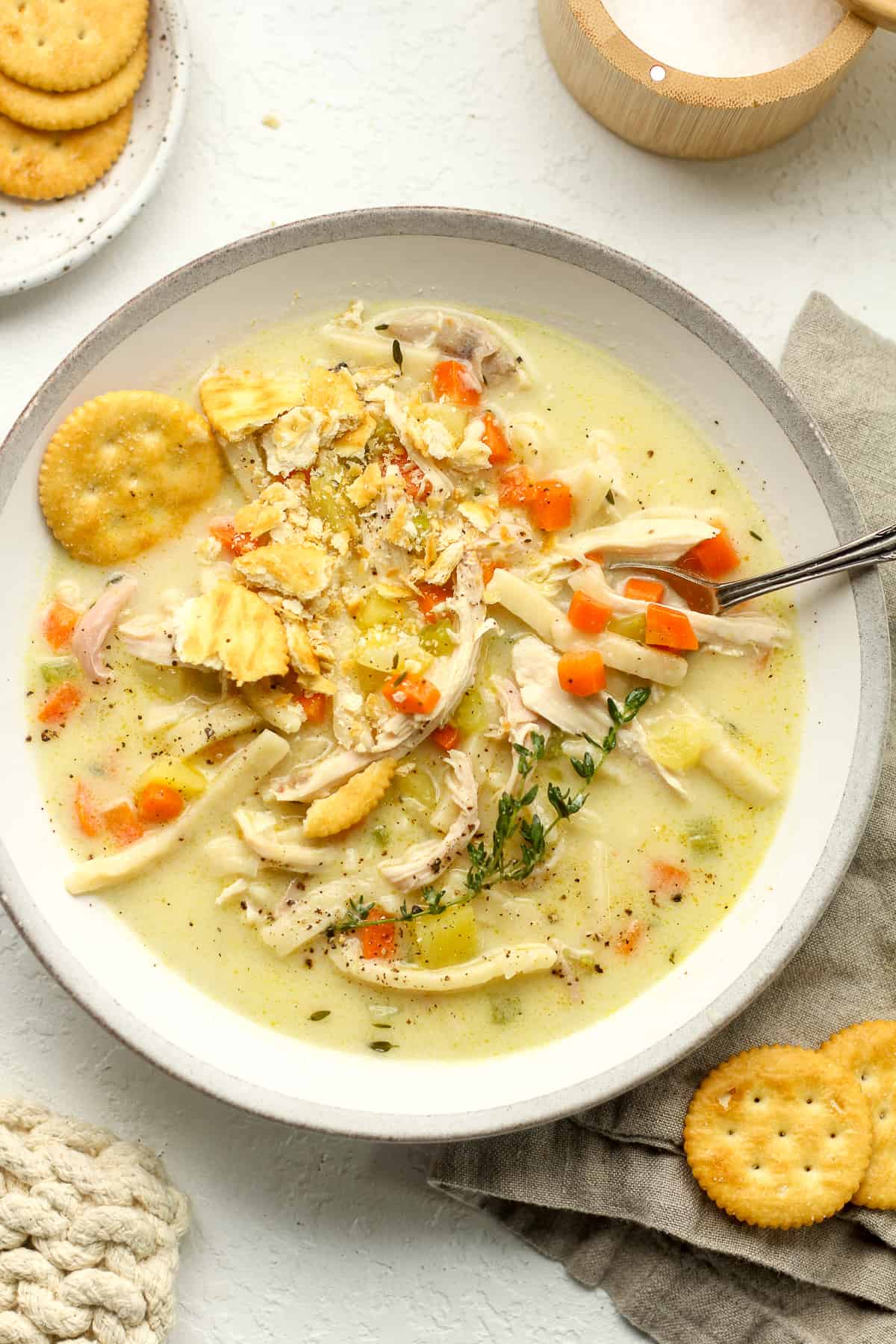 A gray and white bowl of chicken noodle soup.