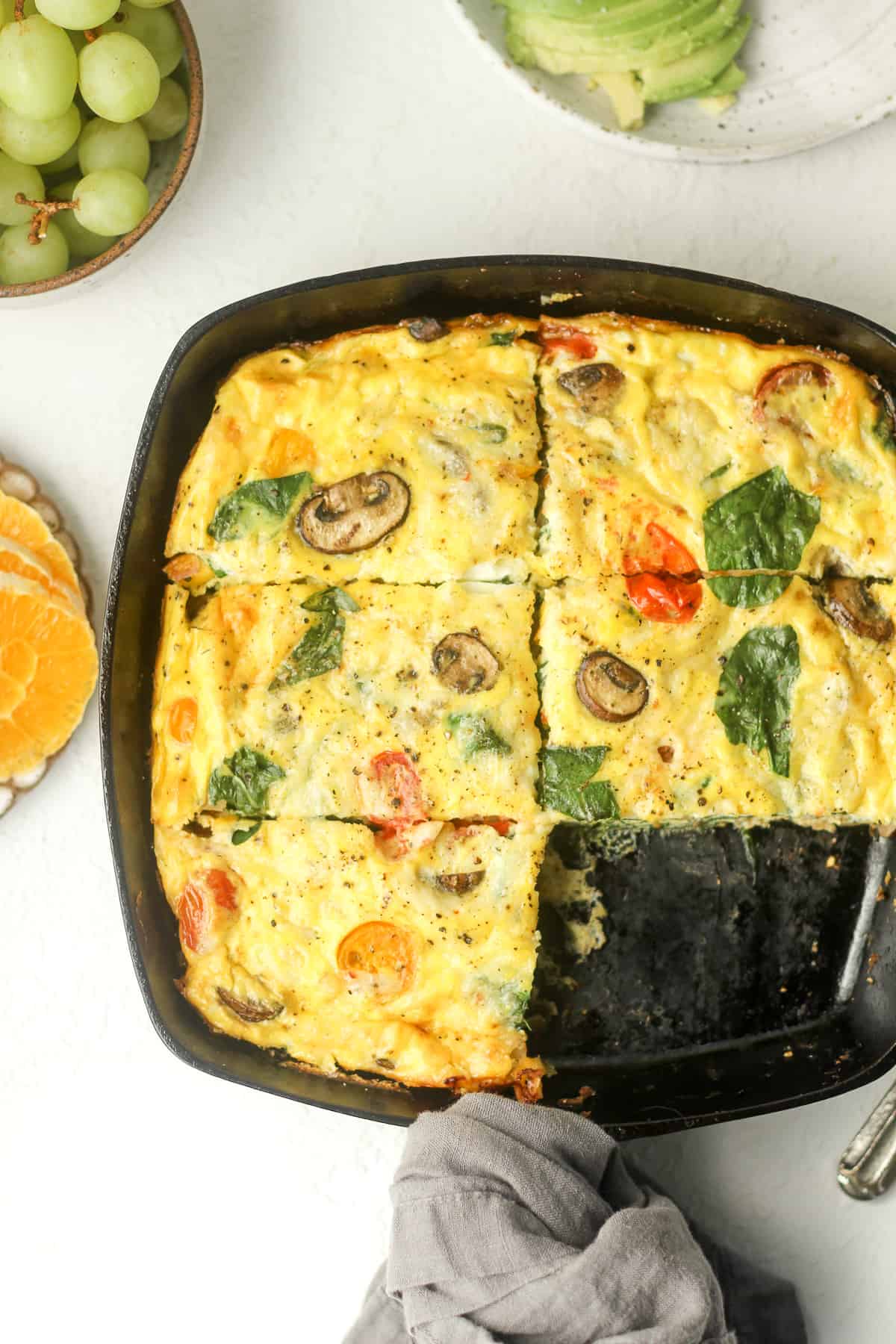Overhead view of a skillet of veggie frittata sliced into pieces.