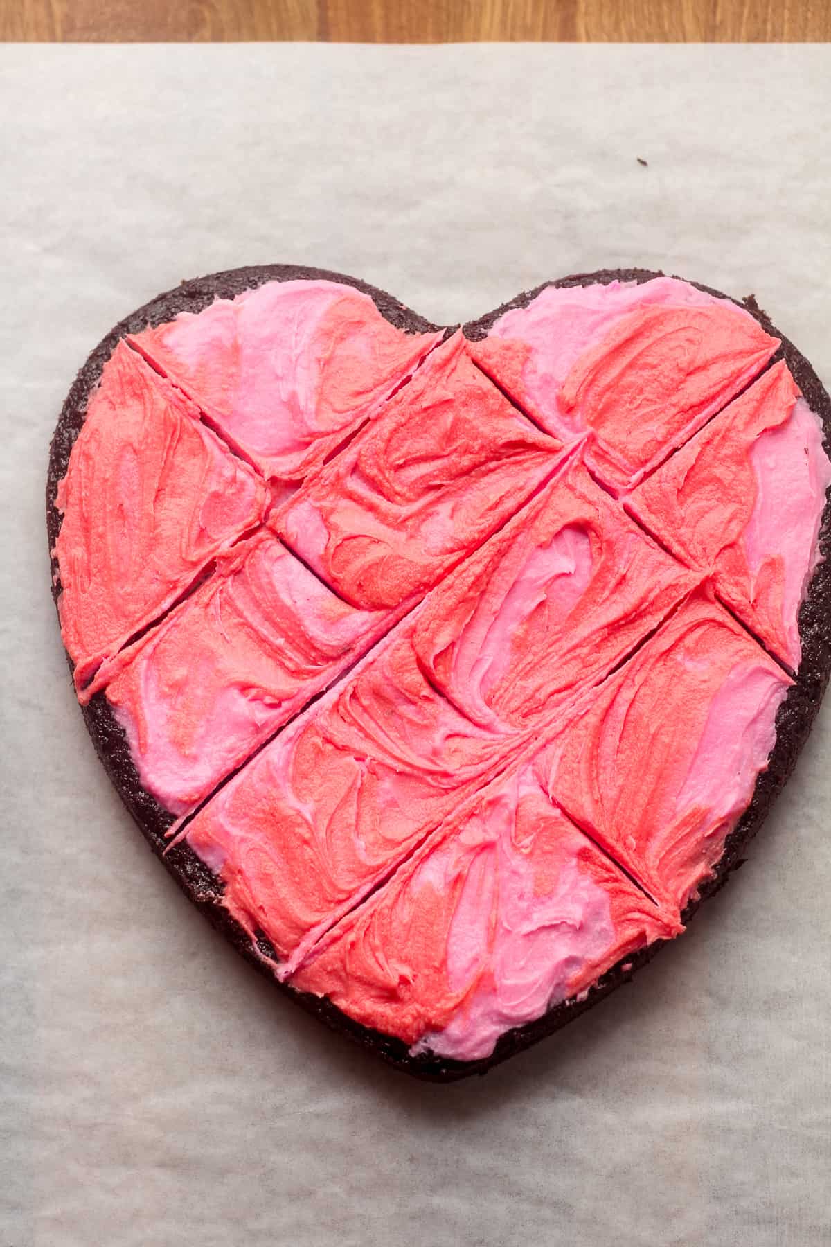 A heart shaped chocolate cake with pink and red buttercream frosting.
