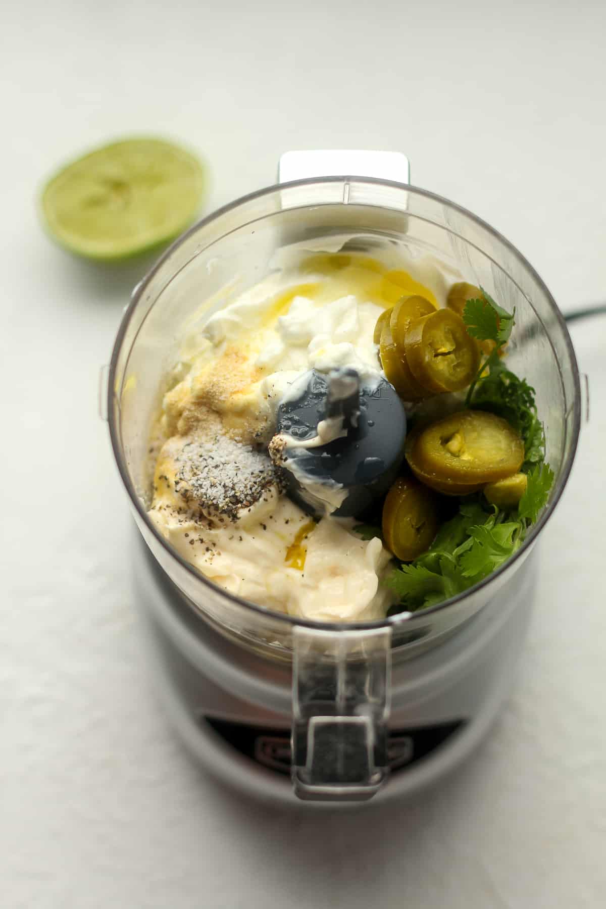 Overhead view of a small food processor of the ingredients for jalapeno ranch dressing.