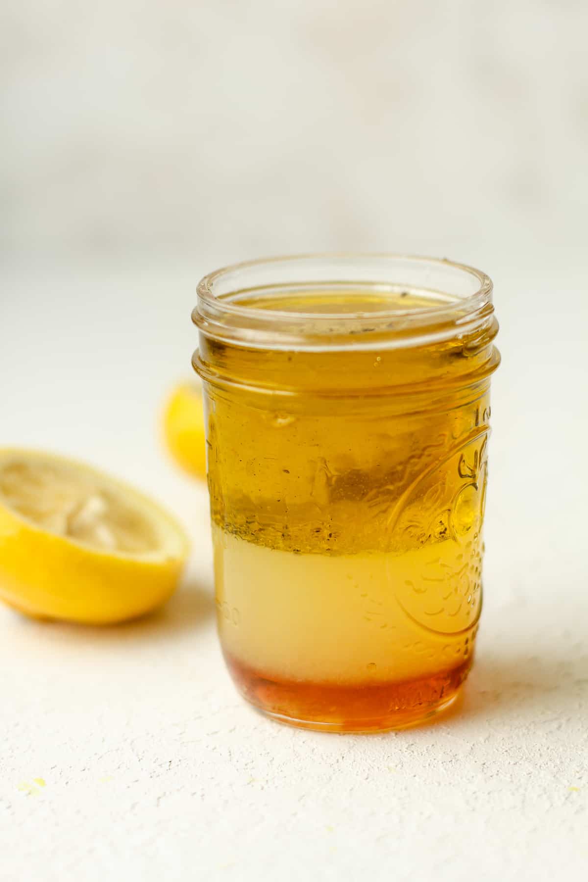 Side view of a jar of honey lemon dressing before shaking.