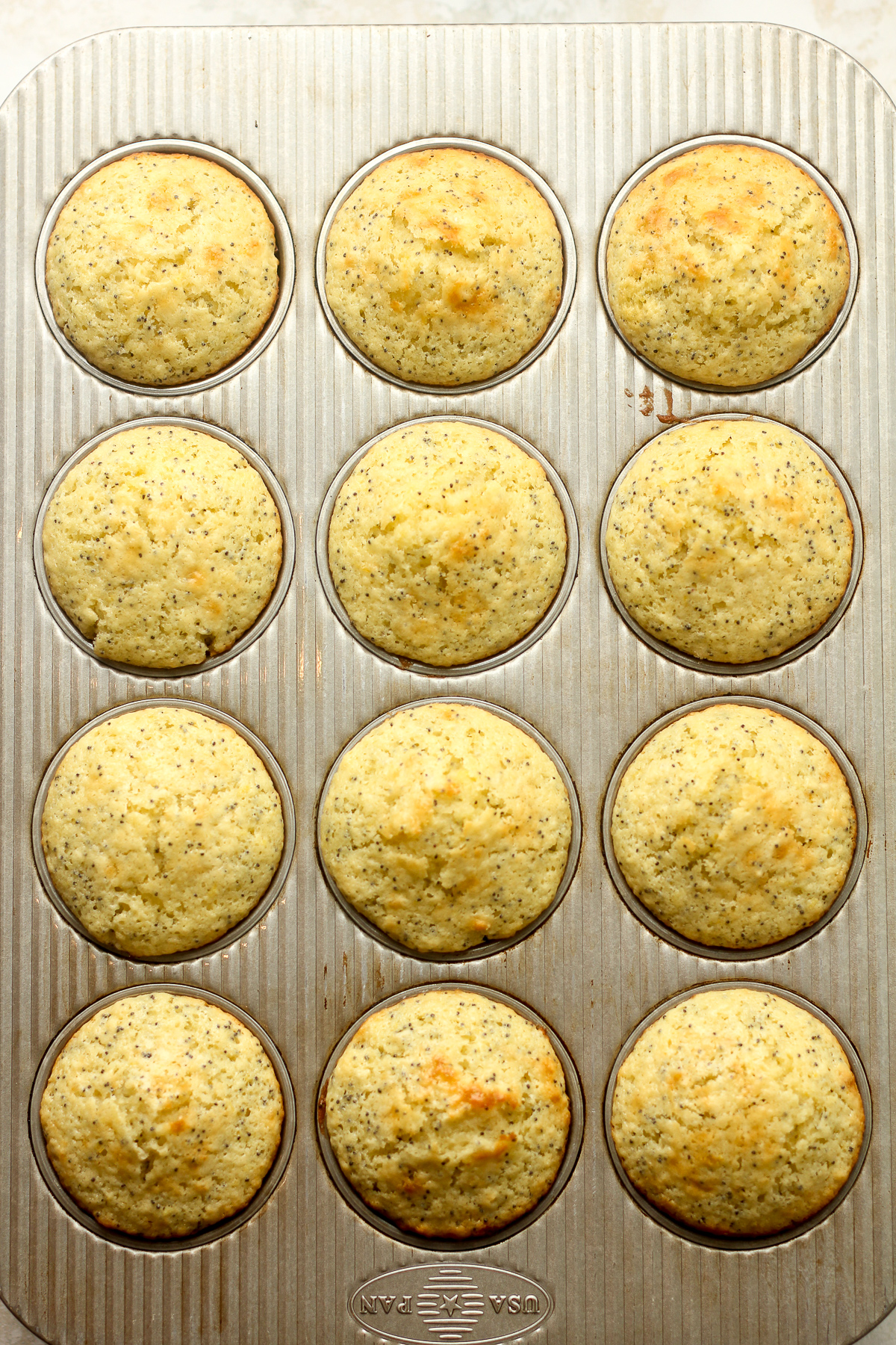 The just baked lemon muffins in a muffin tin.