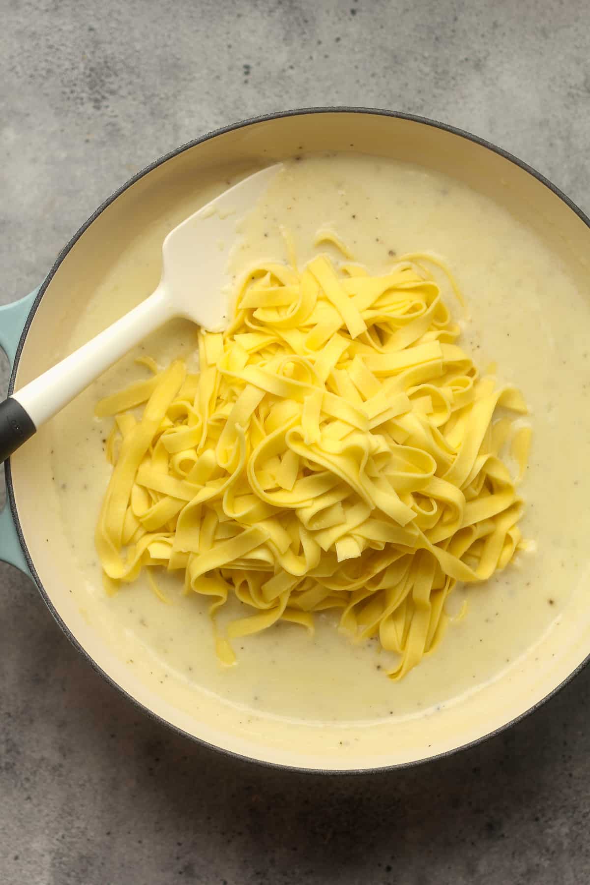 A pot of the creamy sauce with noodles on top.