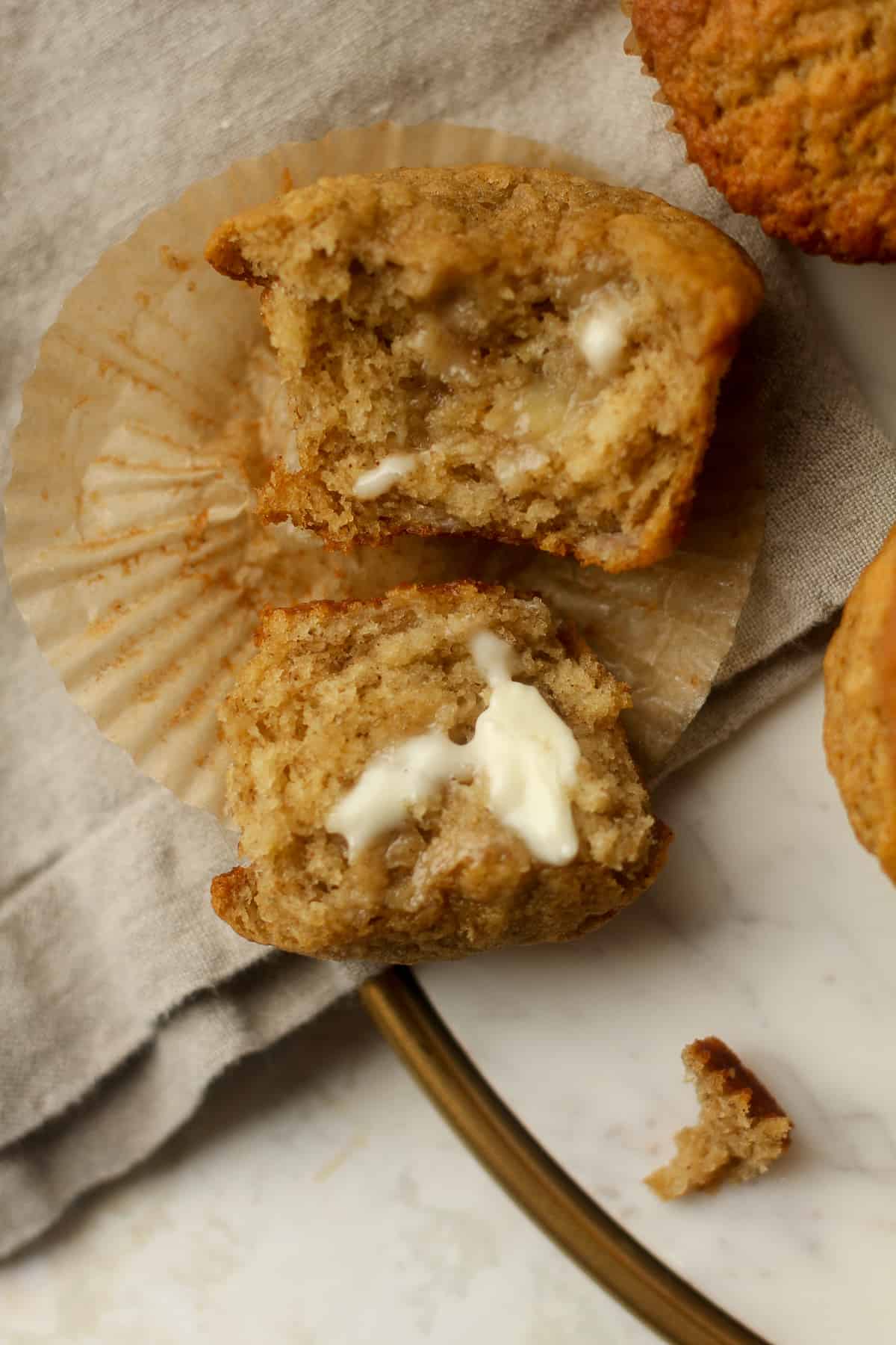 Overhead view of a banana muffin torn in half with butter.