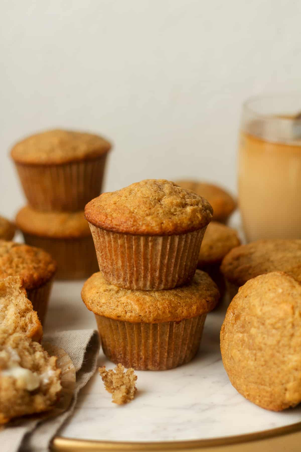 Side view of a tray of moist banana muffins with a cup of coffee in the background.
