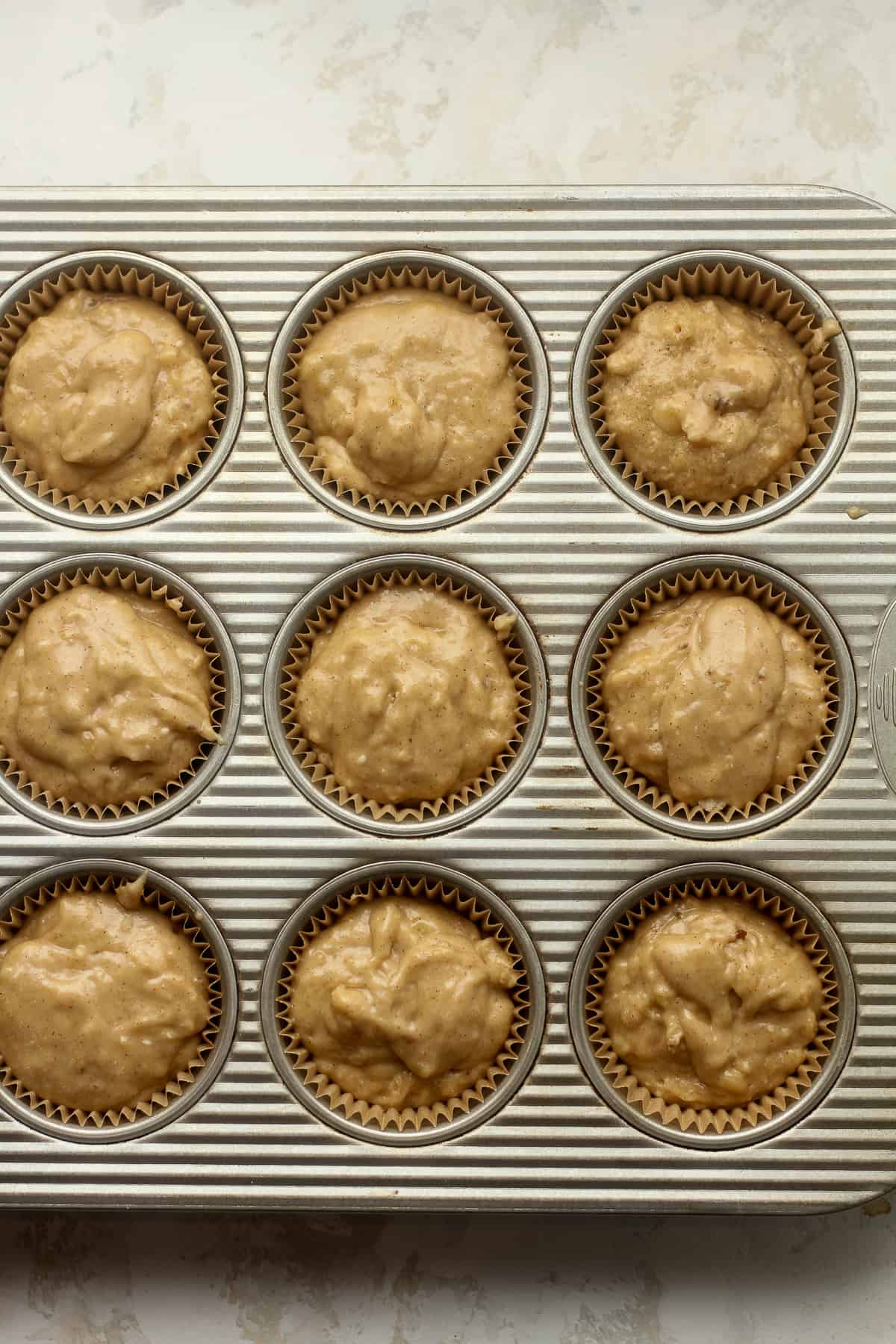 A muffin pan with liners and batter inside.