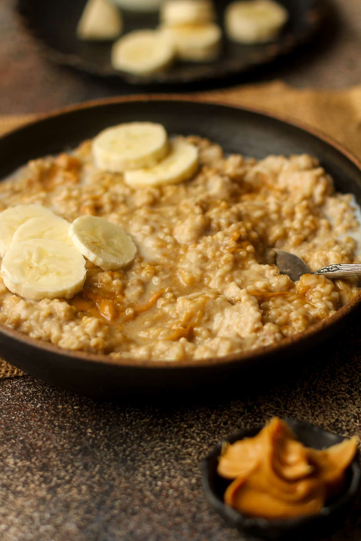 Side view of a bowl of banana steel cut oats with peanut butter.