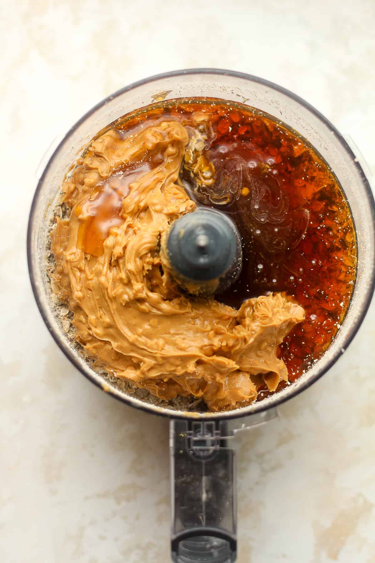 A food processor of the dry ingredients topped with peanut butter and honey.