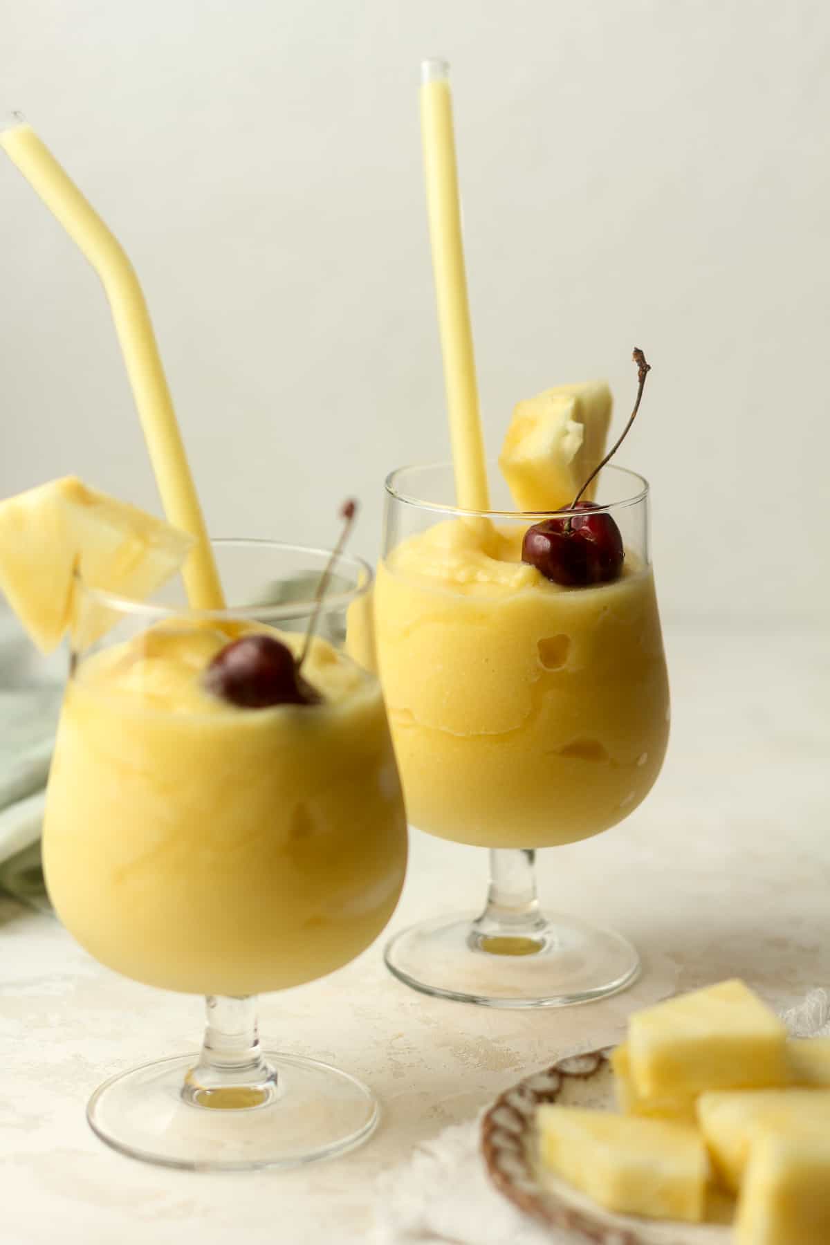 Side view of two Pina coladas with glass straws.