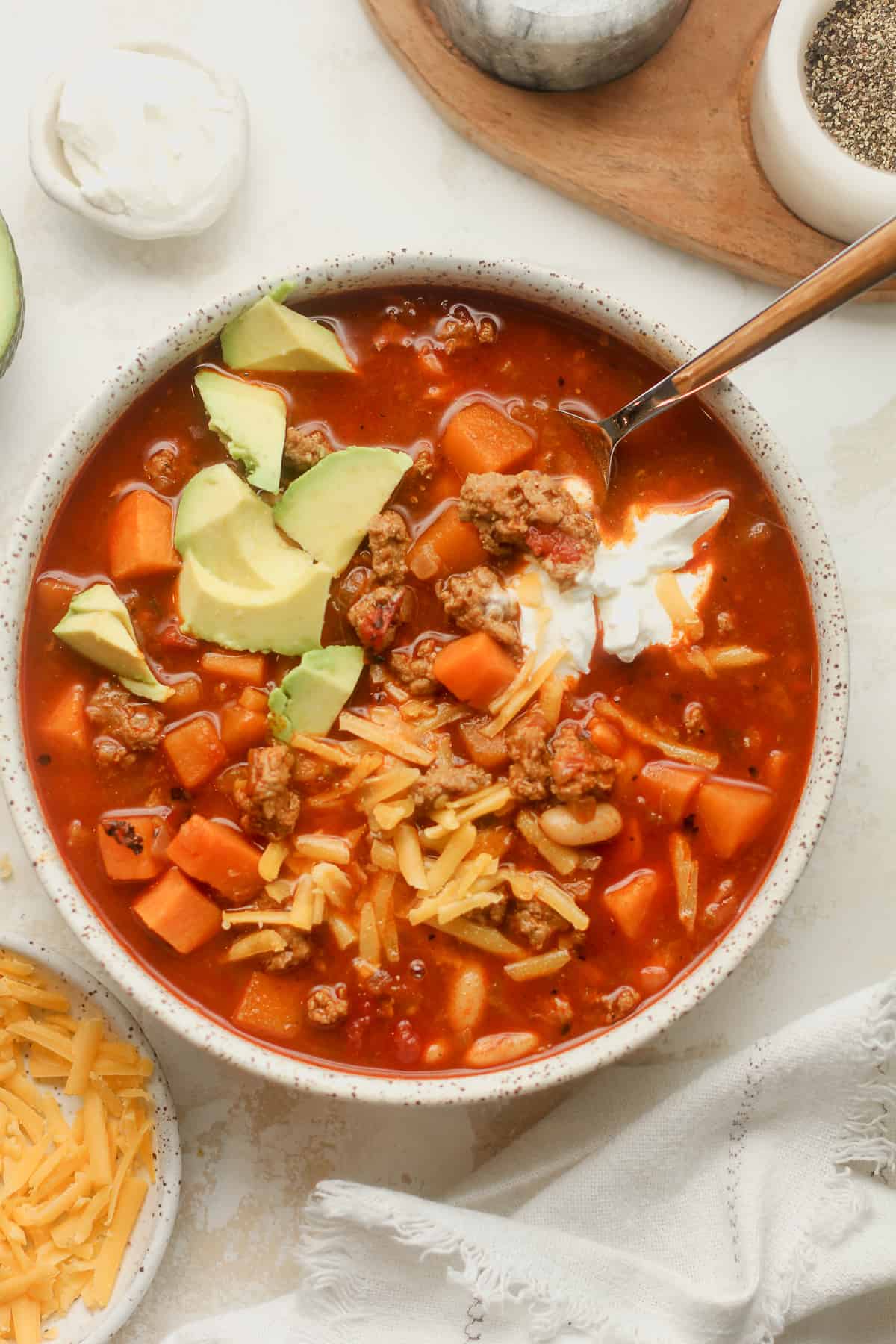 A bowl of turkey chili with sweet potatoes and other toppings.
