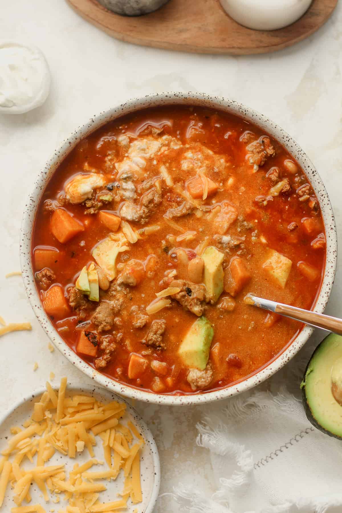 A bowl of sweet potato turkey chili with toppings mixed in.