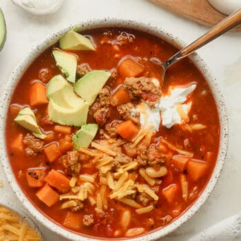 Closeup on a bowl of sweet potato turkey chili with avocado, cheese, and sour cream.