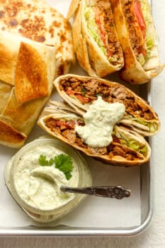 Overhead view of a tray of taco Crunchwraps with jalapeno ranch dressing.