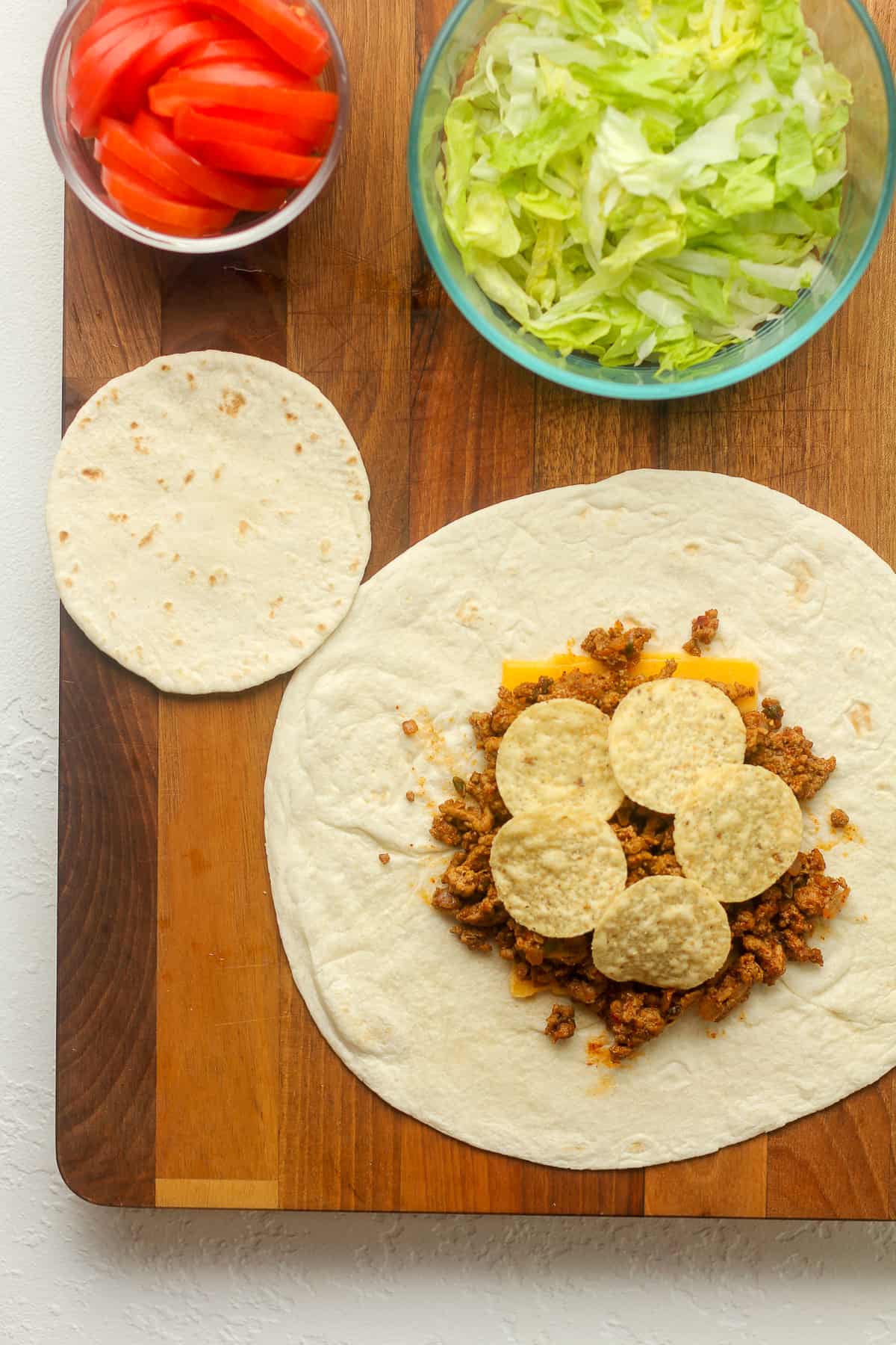 Overhead view of a board with a large tortilla and some of the toppings.