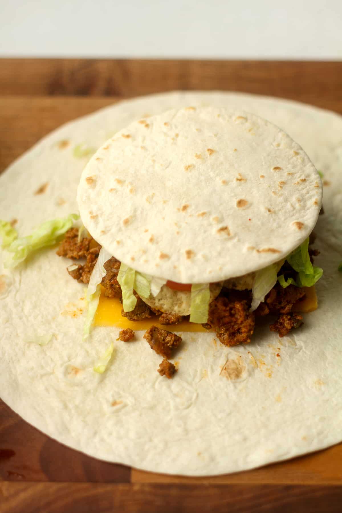 Side view of a large tortilla topped with fillings and a small tortilla on top.