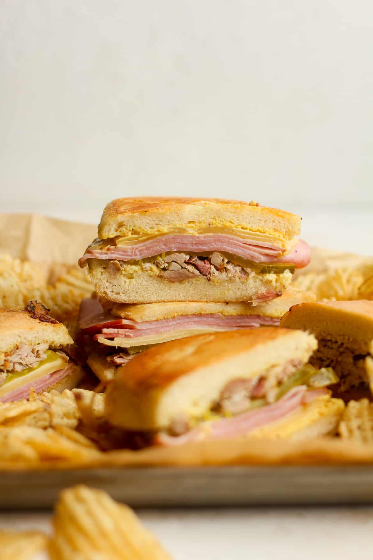 Some stacked Cuban sandwiches and chips.