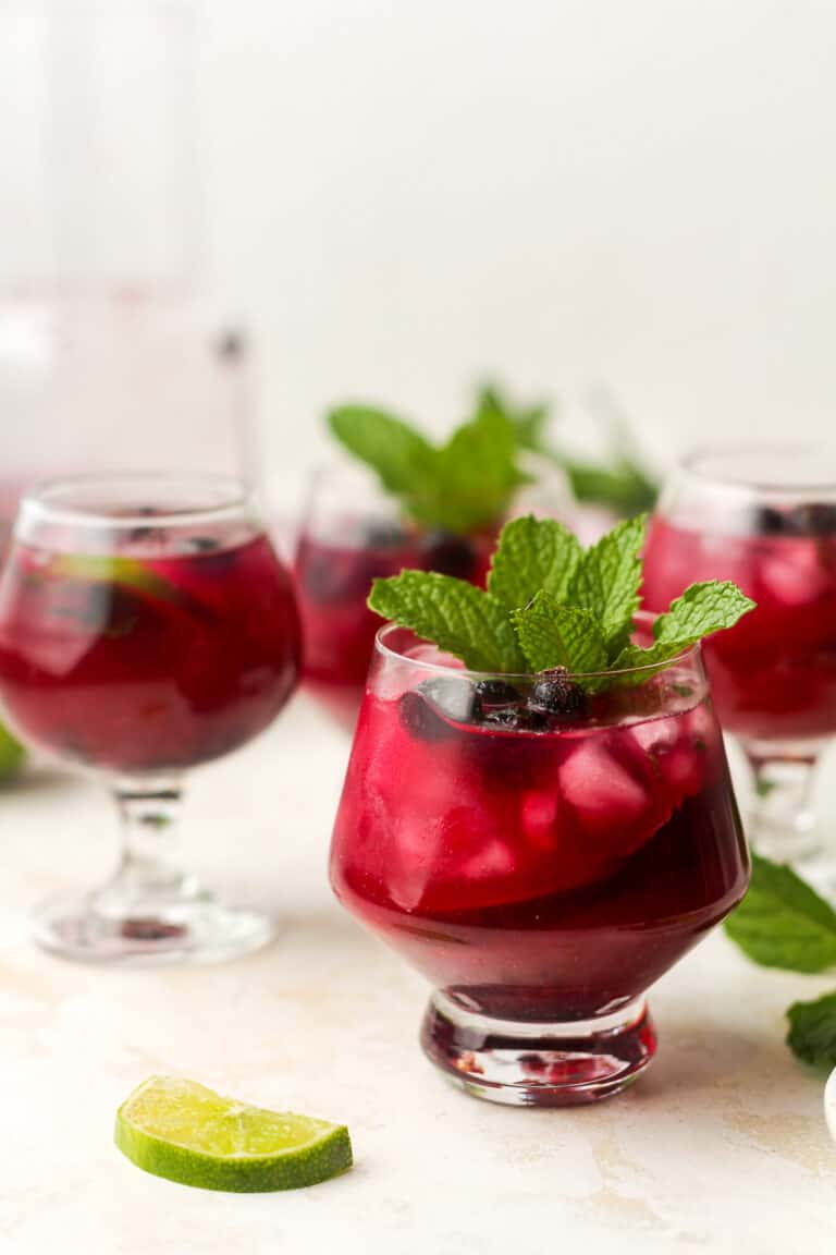 Side view of four virgin blueberry drinks with mint leaves.